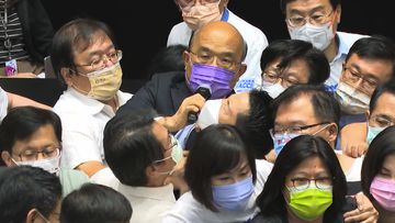 Premier Su Tseng-chang, in purple mask, tries to make a policy speech amid a scuffle between opposition Nationalist party and ruling Democratic Progressive Party lawmakers during a parliament session in Taipei. 