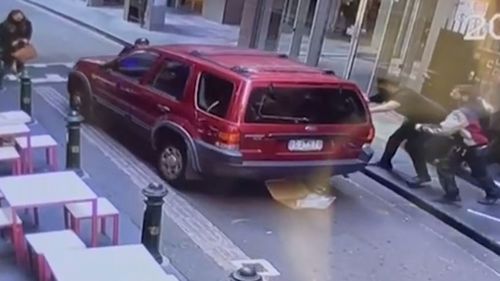 A major manhunt is underway for a man who stole a car in a Melbourne laneway. The owner was left with serious injuries after he clung onto the bonnet of his car to stop thief from driving off. 