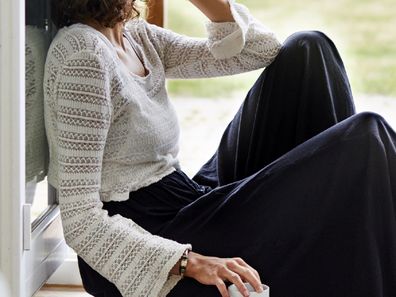 Woman sad sitting on floor with cup of tea