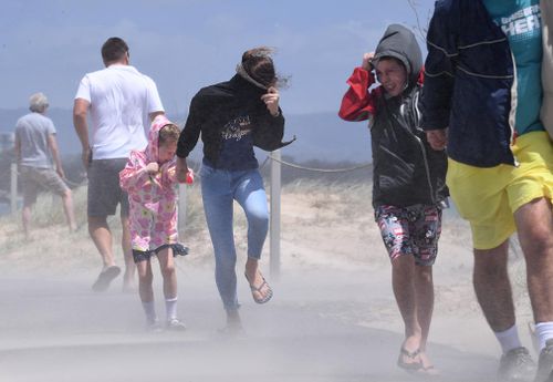 People struggle with blowing sand and high winds on the Gold Coast.