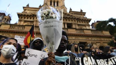 A man holds up a bunch of flowers at Sydney's Black Lives Matter protest. 