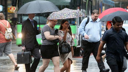 Pedestrians walk through the Brisbane CBD during rain. (AAP)