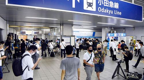 Police and journalists gather at Soshigaya Okura Station after the stabbing on a commuter train.