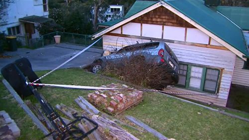 The driver was uninjured, however a crane will be required to remove the car. (9NEWS)
