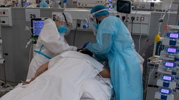 Healthcare staff wearing PPE treat a COVID-19 patient at a hospital in Madrid, Spain.