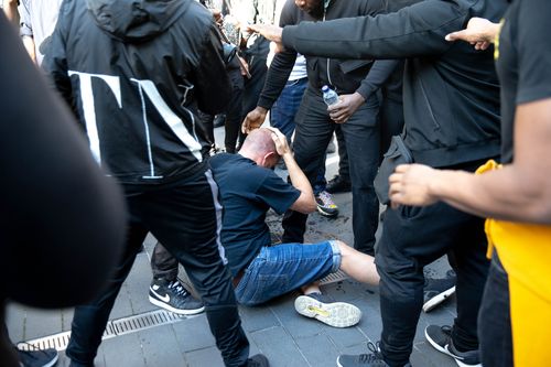 The injured man sits stunned on the ground, after he was rescued by Patrick Hutchinson and his friends.