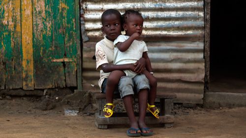 Children sit in front of their home in the St. Paul Bridge neighborhood of Monrovia, Liberia. (AAP)