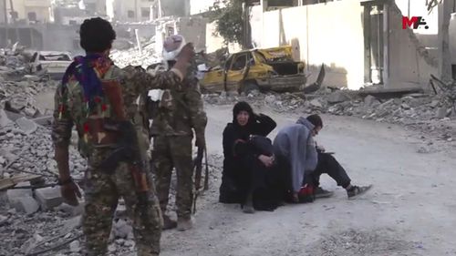 Frame grab from video shows Syrian Democratic Forces fighters standing next to Syrian civilians who fled from areas that still controlled by Islamic State militants in Raqqa, Syria. (Mezopotamya Agency, via AP)