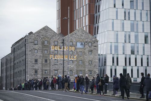 Crowds line the streets by Grand Canal dock as they wait for the funeral procession of Shane MacGowan to make its way through the streets of Dublin ahead of his funeral in Co Tipperary, in Ireland, Friday, Dec. 8, 2023. 