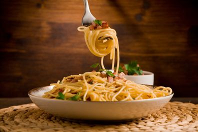Delicious spaghetti with bacon and egg called 'alla carbonara' on wooden table
