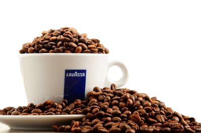 Coffee beans in and around a Lavazza labelled cup 