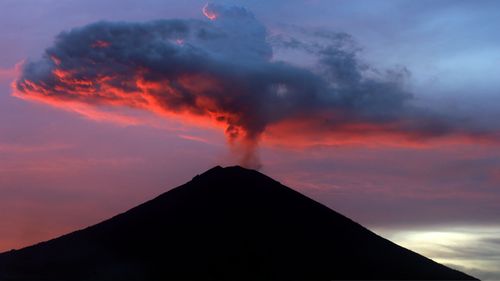 Clouds of ash from the Mount Agung volcano are lit with warm sunset light in Karangasem, Bali, Indonesia on Thursday, November 30. (AAP)