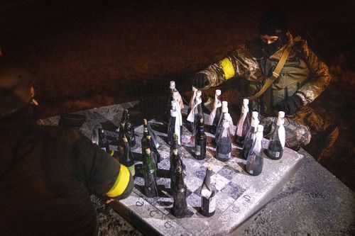 Members of a Territorial Defence unit play checkers with molotov cocktails while guarding a barricade after curfew on the outskirts of eastern Kyiv.