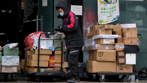 Un lucrător de la o companie privată de livrare, purtând o mască facială, sortează pachetele în centrul său de distribuție din Beijing.