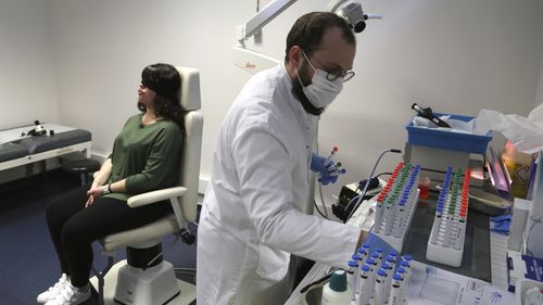 Dr. Clair Vandersteen, right, assembles tubes of odors to waft under the nose of a blindfolded patient, Gabriella Forgione, during tests in a hospital in Nice, France, on Monday, Feb. 8, 2021