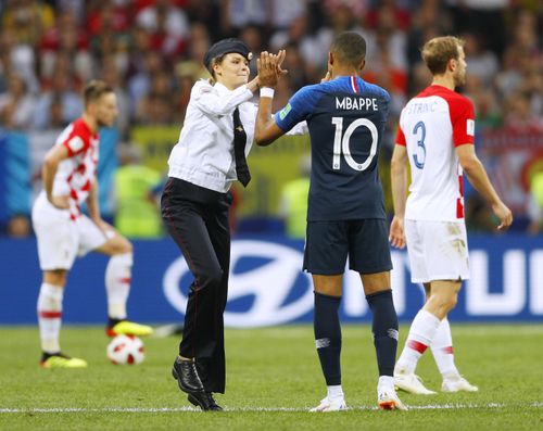 An intruder (L) high-fives Kylian Mbappe of France during the second half of the World Cup final between France and Croatia at Luzhniki Stadium in Moscow on July 15, 2018. Russian protest group and musical act Pussy Riot has claimed responsibility for the incident. (Kyodo via AP Images)