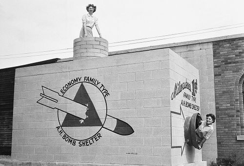 Beverly Wysocki, top, and Marie Graskamp, right, emerge from a new bomb shelter on display in the US in 1958. (AAP)