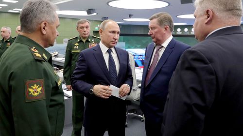 Defence Minister Sergei Shoigu, Army General Valery Gerasimov, Russian President Vladimir Putin, and Russian special presidential representative Sergei Ivanov speak at the National Defense Control Center in Moscow.