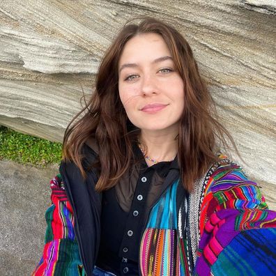 Queer actress and influencer Emma Horn poses in a rainbow jacket.