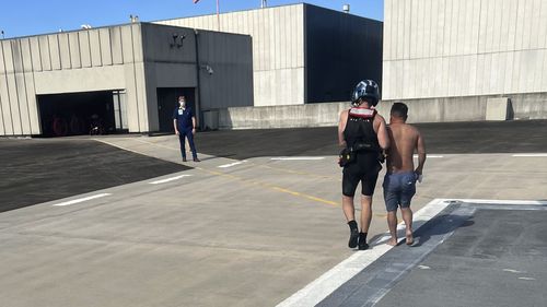 In this image provided by the U.S. Coast Guard, a Coast Guard Station New Orleans rescue swimmer escorts a rescued boater into University Medical Center New Orleans on Sunday, Oct. 9, 2022, in New Orleans, La. Three men whose fishing boat sank in the Gulf of Mexico off the Louisiana coast were rescued after surviving for more than a day despite being attacked by sharks that inflicted deep cuts on their hands and shredded one of their life jackets, according to their rescuers. 