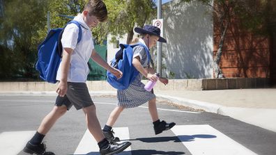 School children crossing the road safely at the cross walk. 