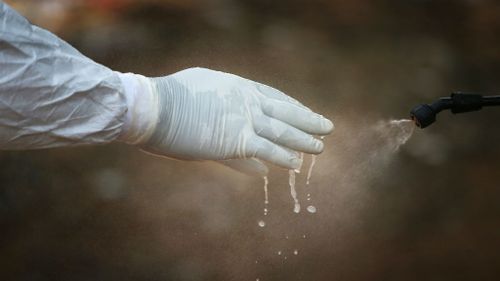 A Liberian health department burial team disinfects their protective clothing after retreiving the body of a woman suspected of dying of the Ebola virus. (Getty Images)