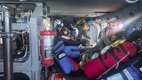 In this image provided by the U.S. Coast Guard, a Coast Guard Air Station New Orleans MH-60 Jayhawk aircrew treats three rescued boaters for injuries Sunday, Oct. 9, 2022, approximately 25 miles offshore from Empire, La. Three men whose fishing boat sank in the Gulf of Mexico off the Louisiana coast were rescued after surviving for more than a day despite being attacked by sharks that inflicted deep cuts on their hands and shredded one of their life jackets, according to their rescuers. 