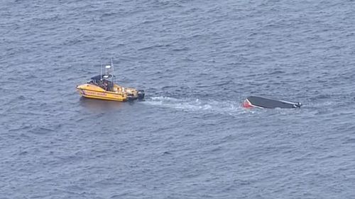 The Coast Guard approaches the overturned boat. (9NEWS)