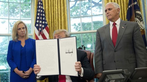 President Donald Trump shows off his executive order with Homeland Security Secretary Kristjen Nielsen and Vice President Mike Pence. (AAP)