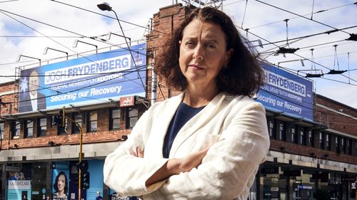 Independent for Kooyong Dr Monique Ryan at Camberwell Junction in Melbourne, standing in front of billboards of Josh Frydenberg.