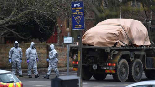 Military in protective clothing prepare to remove vehicles from a car park in Salisbury. (AAP)