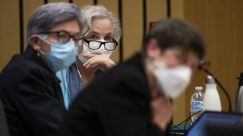 Romance writer Nancy Crampton Brophy, background, accused of killing her husband, Dan Brophy, in June 2018, is surrounded by her defense attorneys in court in Portland.