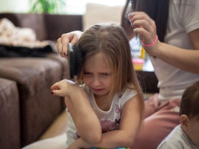 Little girl crying while having her hair brushed