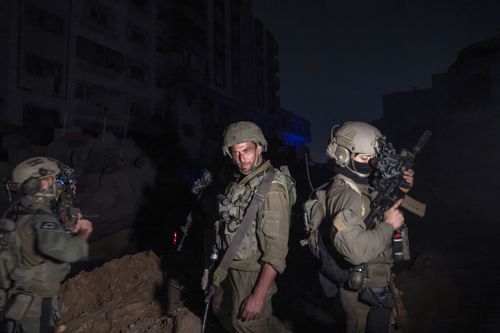 Israeli soldiers escort journalists onto the grounds of Al-Shifa Hospital
