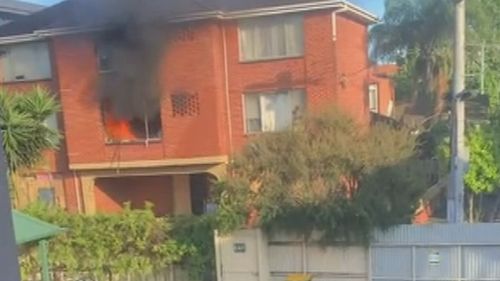 A﻿ man has been saved by his neighbours after they saw him hanging from the window of his burning apartment in Melbourne.