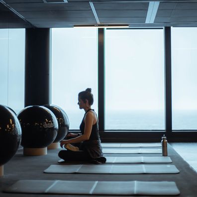 Woman meditating in B-Complex Balance gym in front of the windows. (credit: @ginajoyphoto)