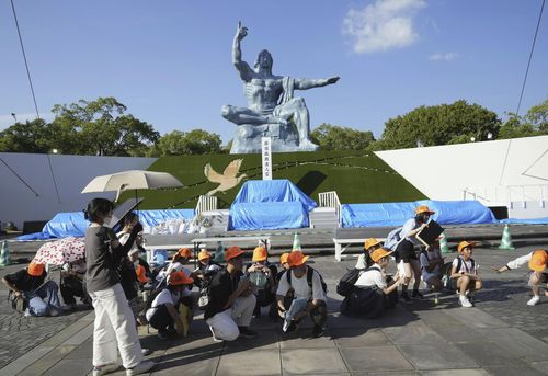 Visitors to the Peace Park crouch as an earthquake alert was issued in Nagasaki, western Japan, Thursday, Aug. 8, 2024 