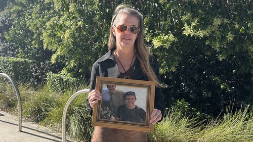 Myfanwy Webb holds a photo of her son Jeremy outside of Lidcombe Coroner's Court on the first day of the inquest into his death on November 17, 2025.