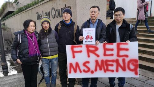 People hold a sign in favor of the release of Huawei Technologies CFO Meng Wanzhou outside the Supreme Court of B.C. during the second day of Meng's bail hearing in Vancouver.