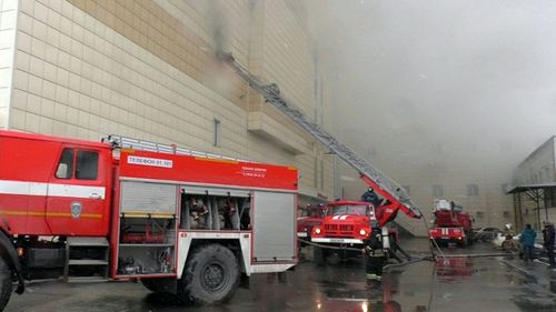 Fire fighters climbing up onto a top floor of a shopping mall Zimnyaya Vishnya on fire in the Siberian city of Kemerovo, Russia.