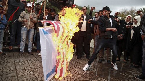 Palestinian demonstrators burn representations of Israeli and American flags during a protest in Gaza City. (AAP)