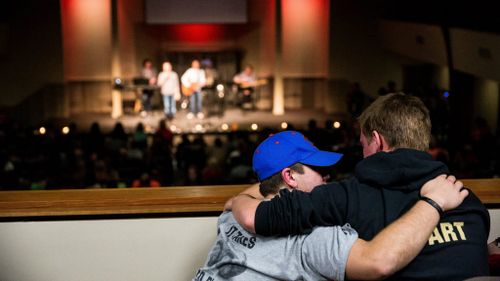 Friends comfort each other during hymns for the shooting victims. (AAP)