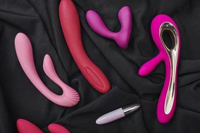 Adult gifts for couples. Close up photo of colorful various sex toys (dildos prostate massager, g-spot vibrators and others) arranged on a black silk fabric.