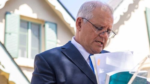 Prime Minister Scott Morrison looks through documents as he delivers the Royal Commission Report into Aged Care.