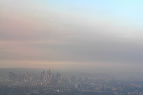 The Sydney skyline and surrounding suburbs is seen against smoke haze from hazard reduction burns. (AAP)