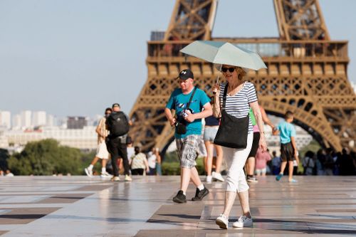 A tourist holds an umbrella as protection from the sun during a heatwave near the Eiffel Tower, in Paris, on June 30, 2025. French authorities put Paris on red alert for extreme heat.