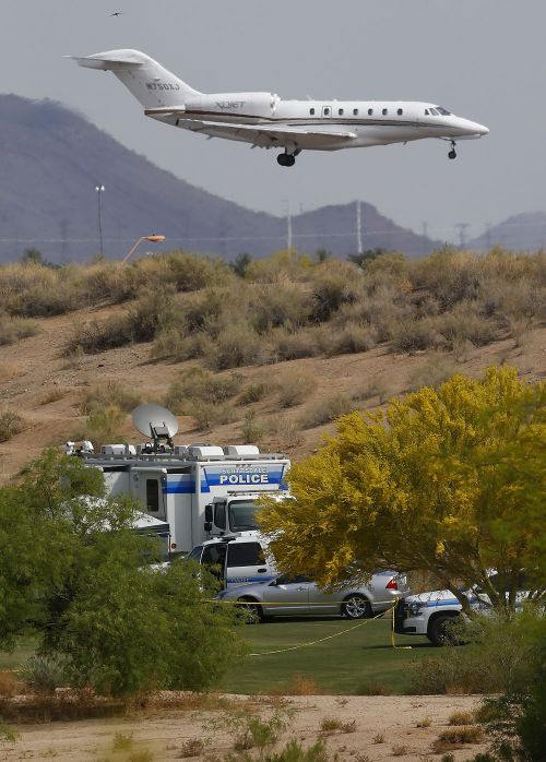 As a jet comes in for a landing at Scottsdale Airport, authorities park on a golf course near the site of the plane crash.