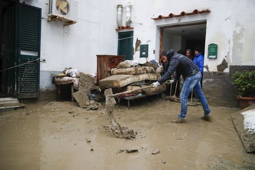 Un uomo rimuove il fango davanti a una casa dopo che una forte pioggia ha provocato frane che hanno fatto crollare edifici e lasciato fino a 12 persone disperse, a Casamicciola, nell'isola di Ischia, nel sud dell'Italia.