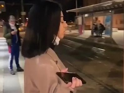 French woman, Sarah, standing on a train platform as two men heckle her.