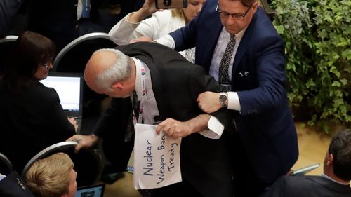 Sam Husseini, seated with the American press corps in Helsinki, was holding a sign reading "nuclear weapon ban treaty". Image: AP